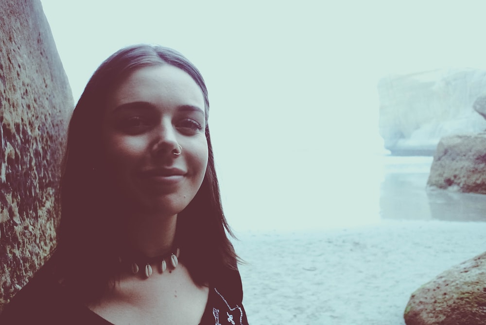 woman taking selfie near body of water and rocks