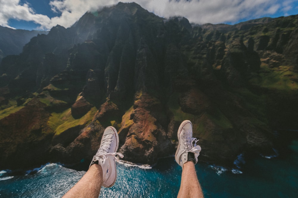 person above mountain and body of water