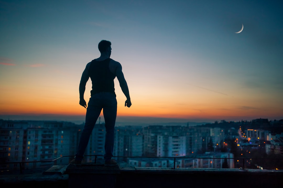 silhouette photography standing on peak front of high-rise buildings