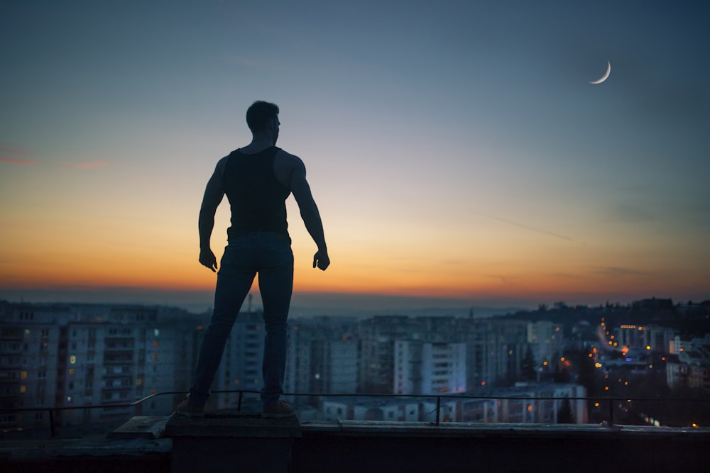 silhouette photography standing on peak front of high-rise buildings