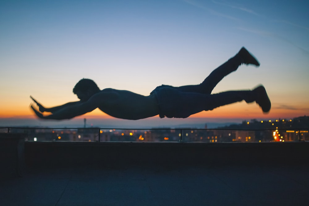 gray scale photo of man falling during golden hour