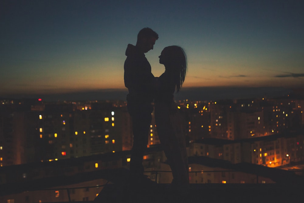 Silhouette eines Mannes und einer Frau, die auf dem Dach des Gebäudes stehen