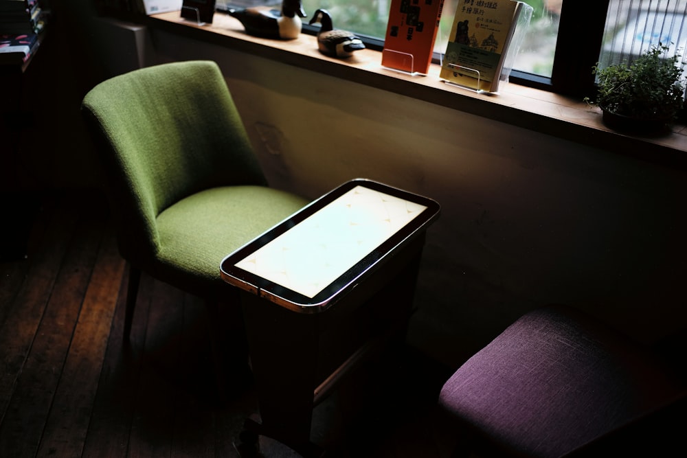 green chair in front of table near window