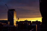 Contractors reviewing blueprints on-site with the city skyline in the background at sunset.