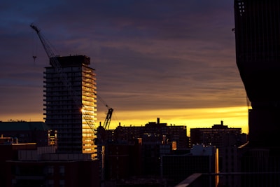 Close-up of hands holding blueprints with a city skyline in the background during sunset.