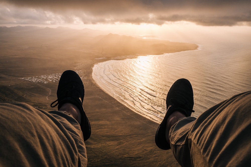 person sitting on cliff near ocean