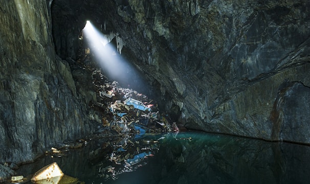 Cossac salvage operatives scavenging ancient wreckage inside a shadowed asteroid cavern, illuminated by green tactical lights.