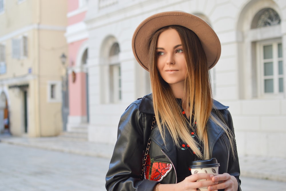 woman looking left side while holding plastic tumbler