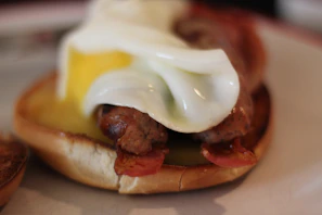 Close-up of a sizzling breakfast sandwich stacked with eggs, bacon, and cheese.