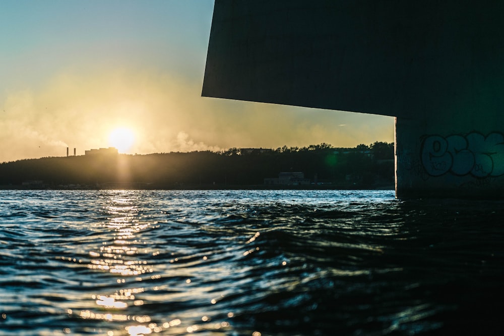 low angle photography of sun behind building on hill over the sea