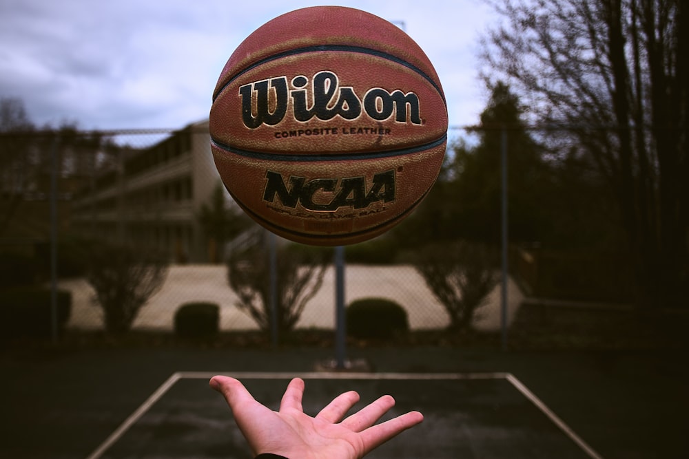 Person, die orangefarbenen Wilson-Basketballball freigibt