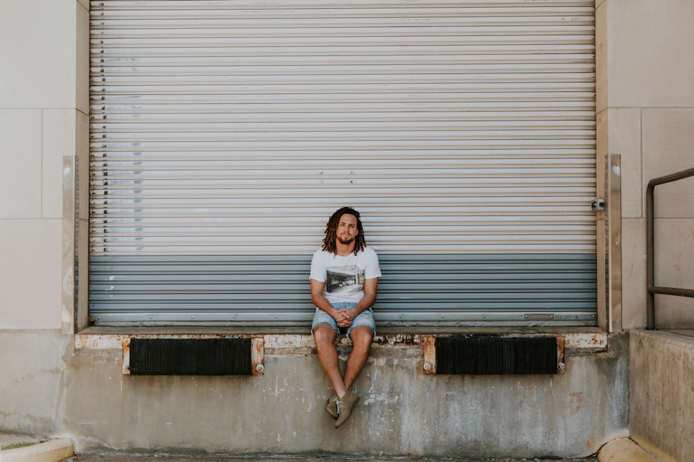 man sitting on pavement in front of roller shutter