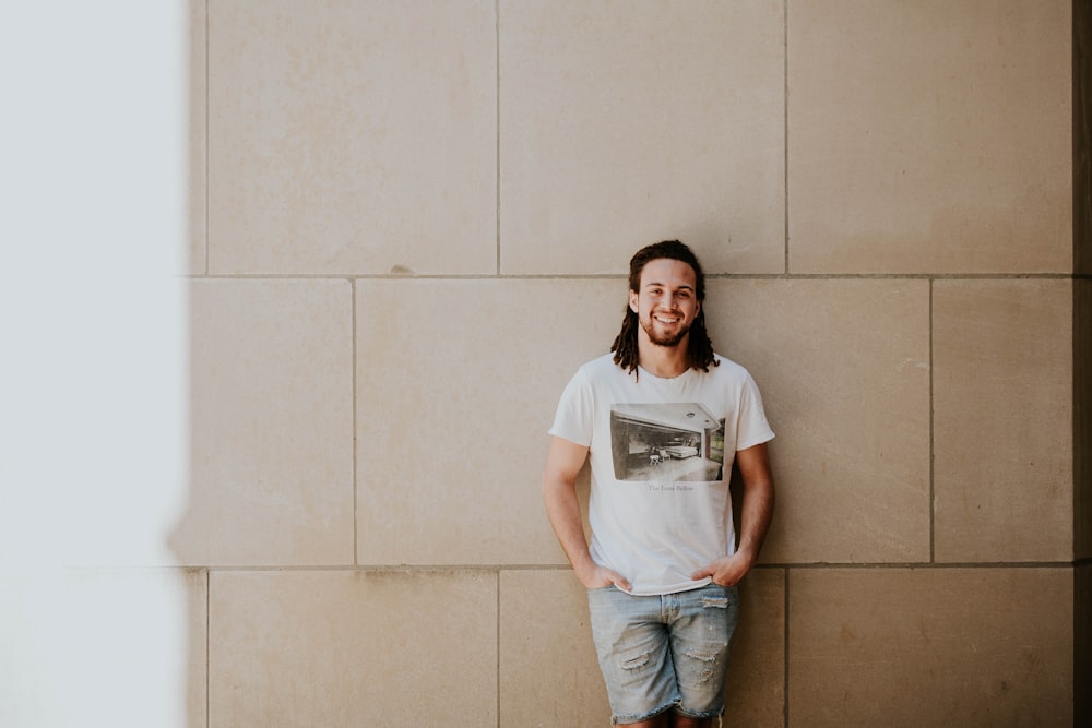 man leaning on white wall