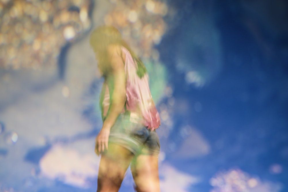 A blurry shot of a woman in shorts against a blue sky