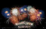 Fireworks bursting in colorful patterns above a lively wedding crowd at night.
