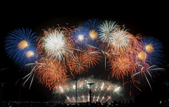 A vibrant night sky lit up with colorful fireworks bursting over a festive crowd.