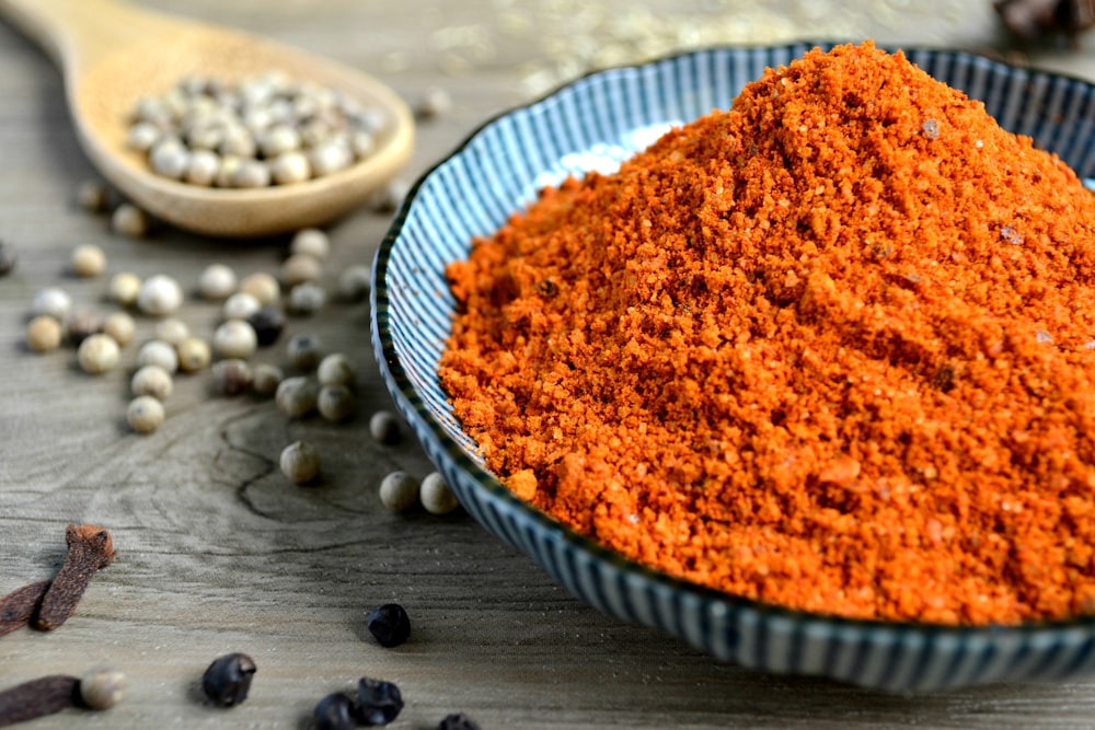 rote Gewürze auf blauer Schüssel mit Paprika auf dem Tisch verstreut