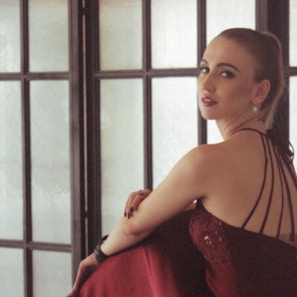 An elegant model showcasing a sleek red evening dress with subtle, intricate details under soft lighting.