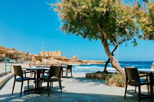 brown wooden table and chairs on beach during daytime in Żebbuġ Malta