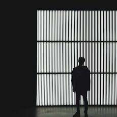 silhouette photo of a person standing near wall in dark room