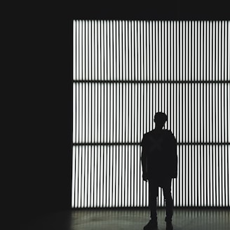 silhouette photo of a person standing near wall in dark room