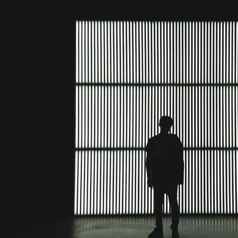 Foto de la silueta de una persona de pie cerca de la pared en el cuarto oscuro