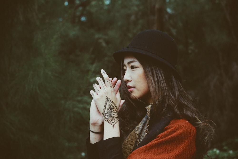 woman wearing red top and black hand clasping her hands