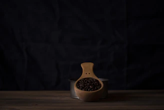 Artisan hand scooping whole coffee beans from a rustic wooden container.