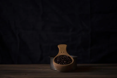 Artisan hand scooping whole coffee beans from a rustic wooden container.