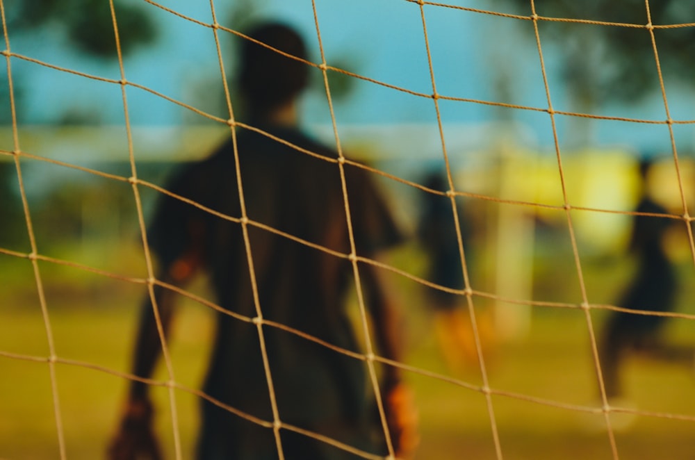 man in black T-shirt through soccer goal post