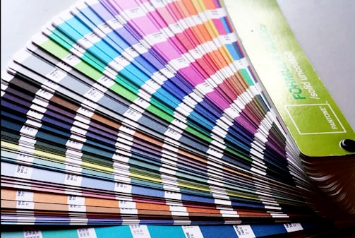 A fan deck of color swatches showcasing a wide range of colors from blues and greens to pinks and browns. The swatches are fanned out, displaying their gradient and color codes.