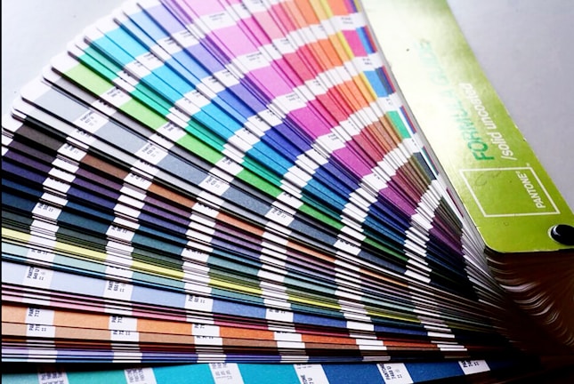 A fan deck of color swatches showcasing a wide range of colors from blues and greens to pinks and browns. The swatches are fanned out, displaying their gradient and color codes.