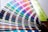 A fan deck of color swatches showcasing a wide range of colors from blues and greens to pinks and browns. The swatches are fanned out, displaying their gradient and color codes.
