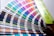 A fan deck of color swatches showcasing a wide range of colors from blues and greens to pinks and browns. The swatches are fanned out, displaying their gradient and color codes.