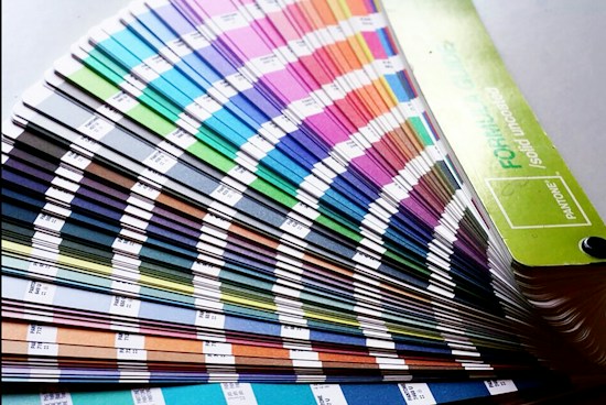 A fan deck of color swatches showcasing a wide range of colors from blues and greens to pinks and browns. The swatches are fanned out, displaying their gradient and color codes.