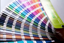 A fan deck of color swatches showcasing a wide range of colors from blues and greens to pinks and browns. The swatches are fanned out, displaying their gradient and color codes.