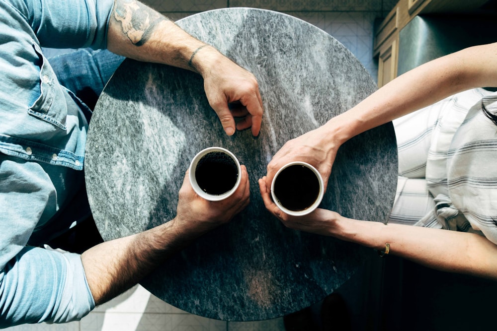 two man and woman holding cups on tables