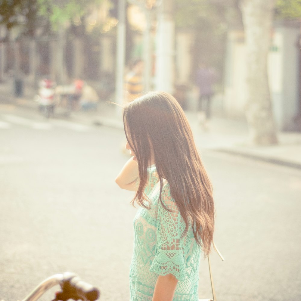 selective focus photo o woman wearing green short-sleeved top standing on roadway