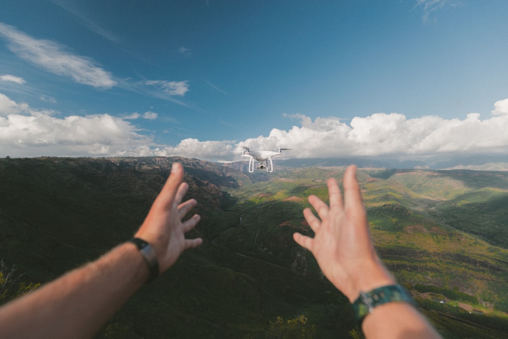 person pointing both hands on white drone during daytime