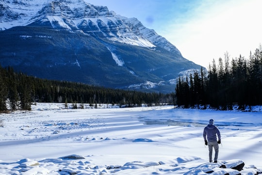 person standing on snow near mountain during daytime in Athabasca Falls Canada