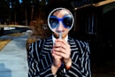 person using magnifying glass enlarging the appearance of his nose and sunglasses