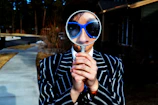 person using magnifying glass enlarging the appearance of his nose and sunglasses