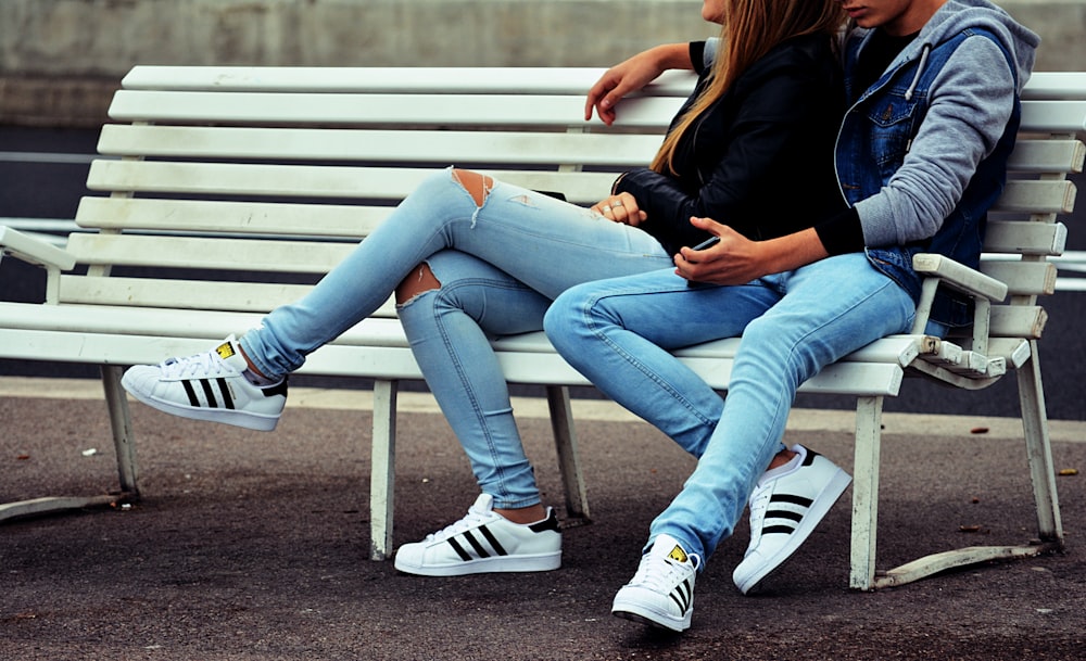 photo of couple sitting on white bench