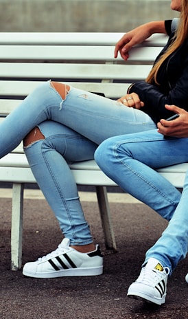 photo of couple sitting on white bench