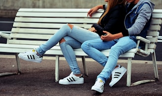 photo of couple sitting on white bench