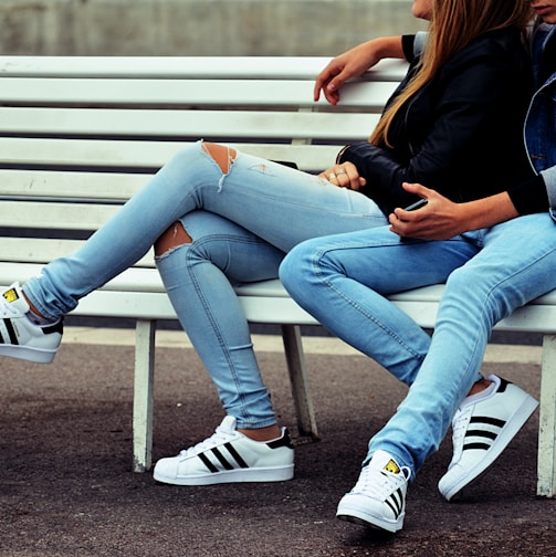 photo of couple sitting on white bench