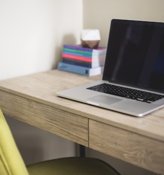 silver and black laptop computer on brown wooden desk beside green leather chair