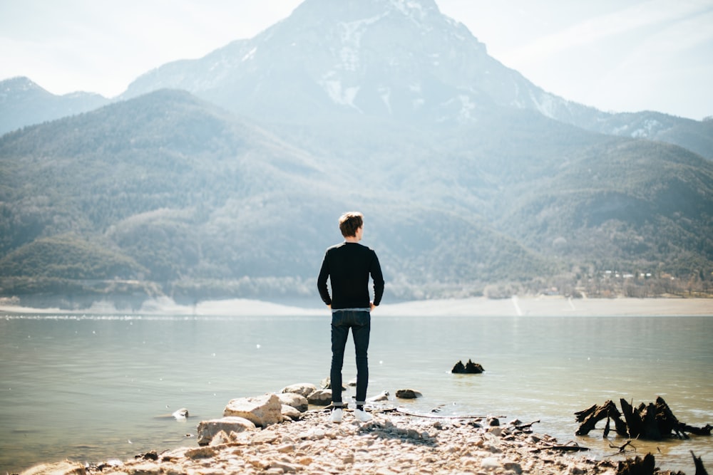Hombre de pie frente al lago durante el día