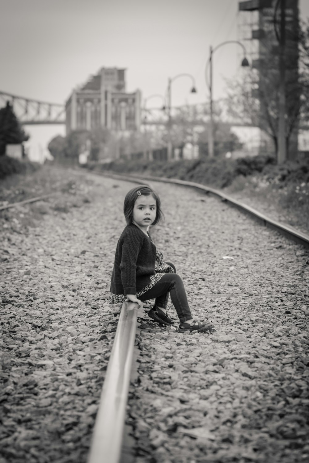 woman in black jacket sitting on train rail during daytime