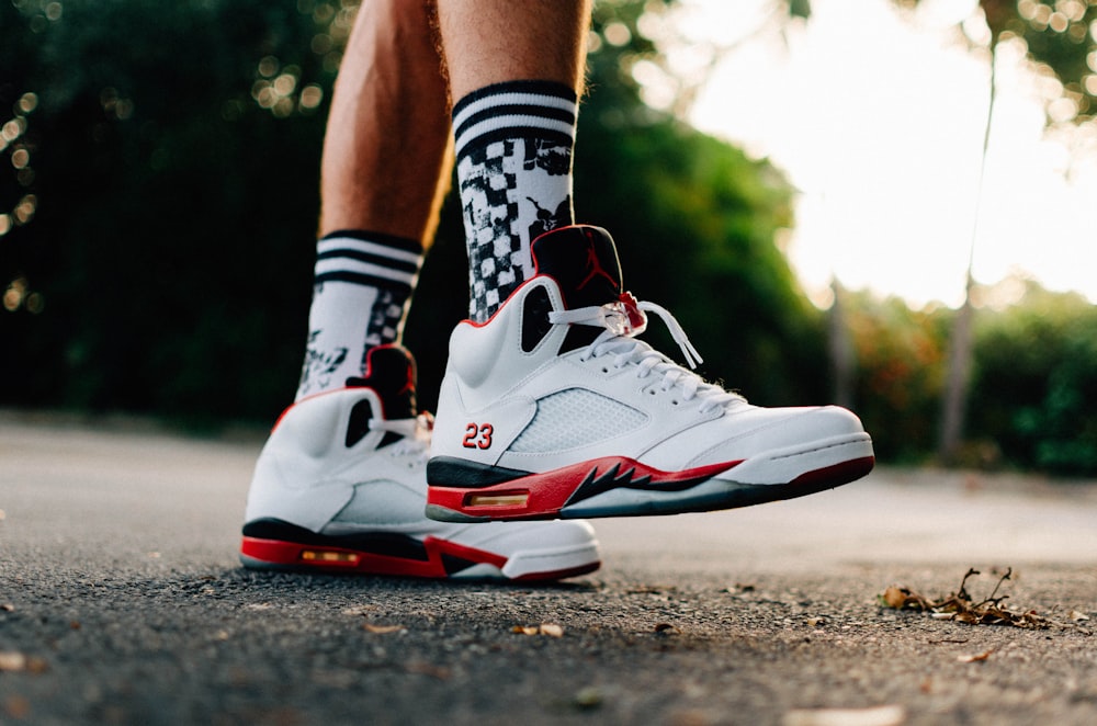 person wearing white-black-and-orange Air Jordan 5 shoes